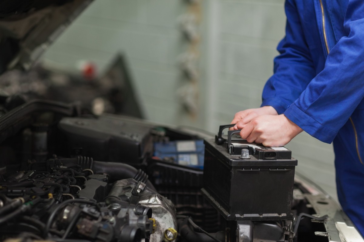 mechanic placing a car battery into a vehicle